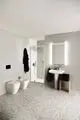 Moderne Badezimmeransicht mit Duschbereich, Waschbecken und WCs in schlichten Formen. Ideal Standard-Produkte sind klar integriert in das minimalistische Design.